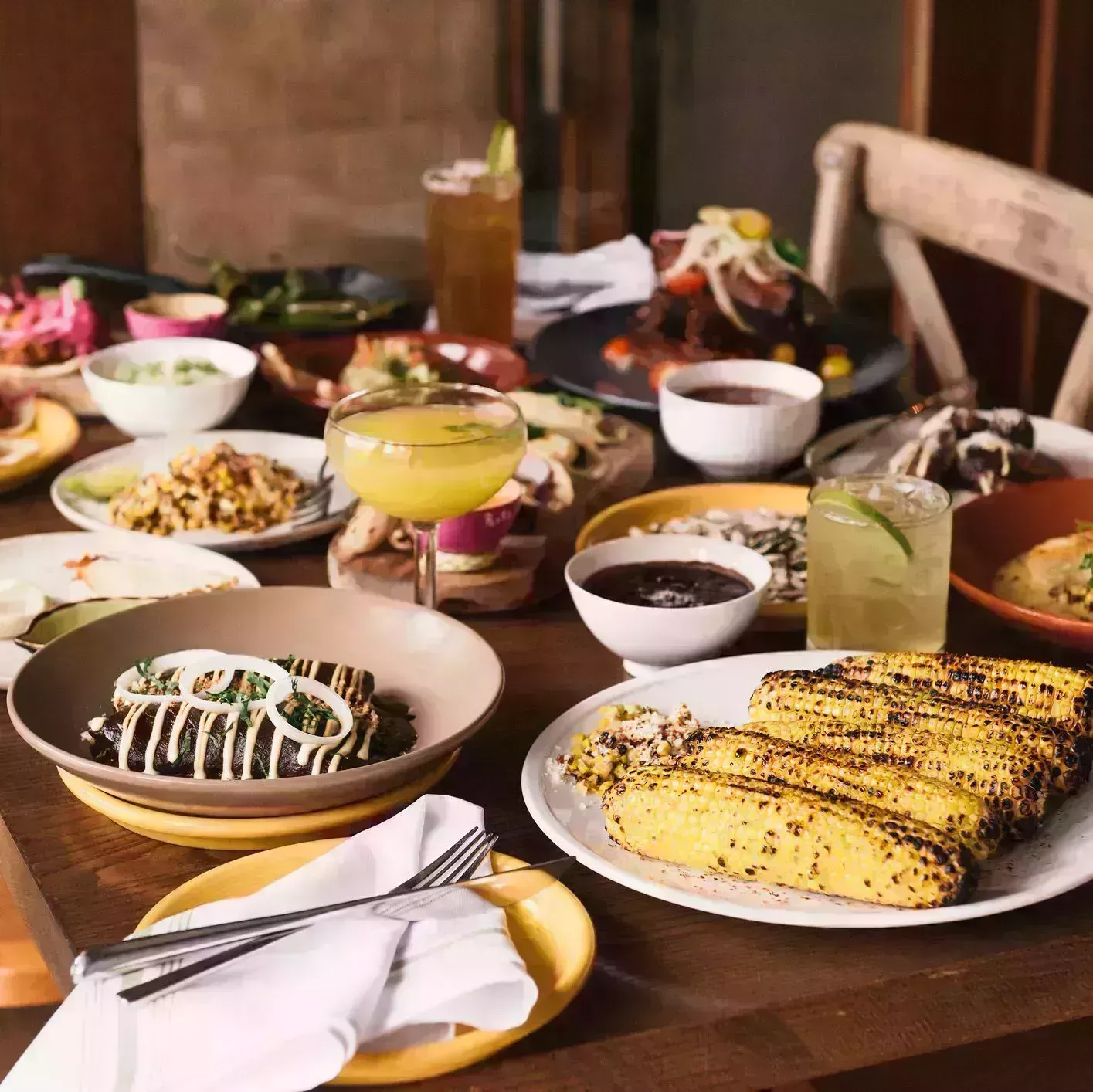 a table full of traditional mexican food, enchiladas, mole, tortillas