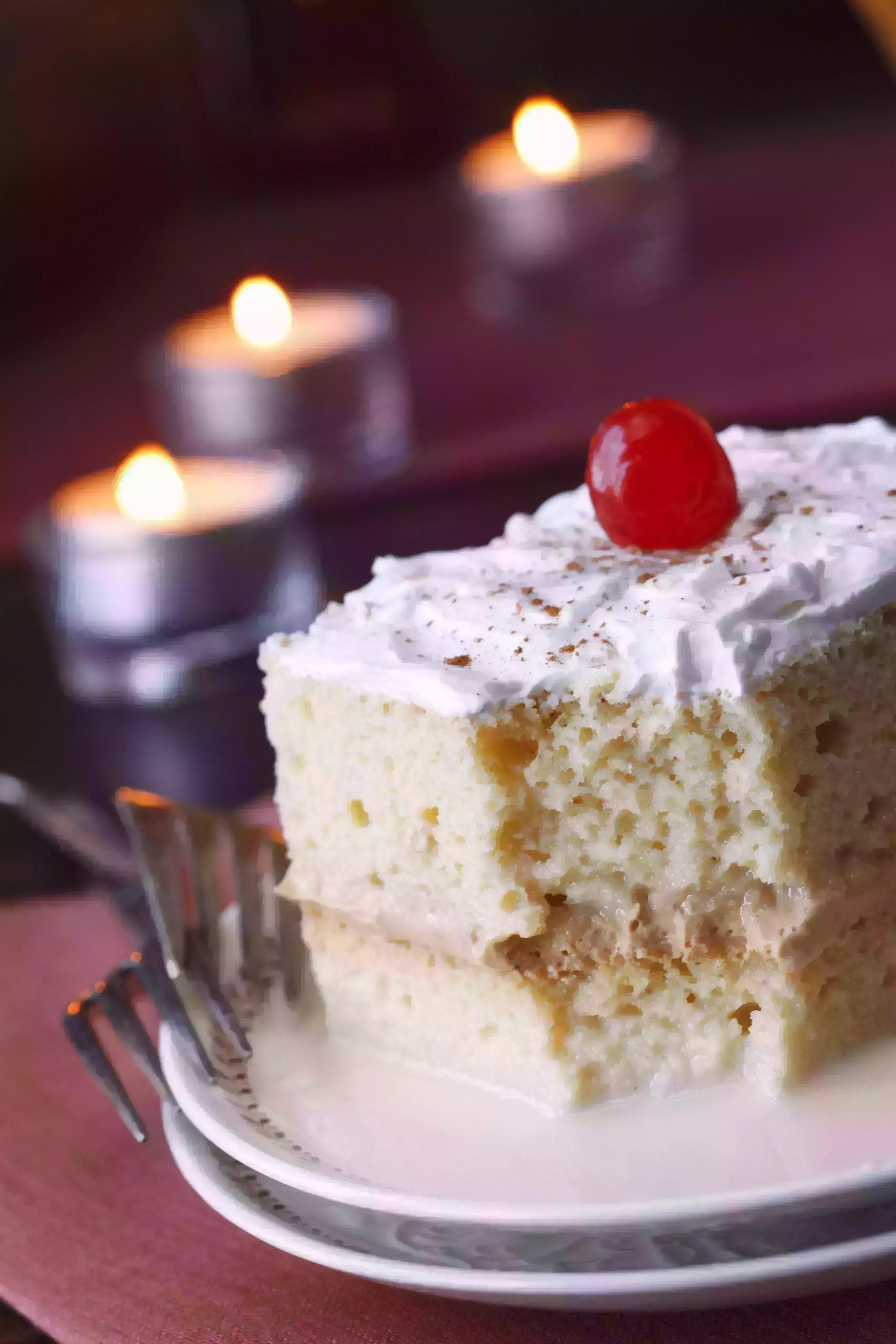 tres leches cake with cinnamon and a cherry partially eaten