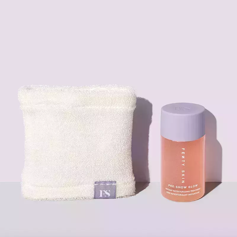 A small clear frosted plastic bottle with lavender cap of the Fenty Skin Pre-Show Glow Instant Retexturizing 10% AHA Treatment with white applicator towel on a purple and gray background 