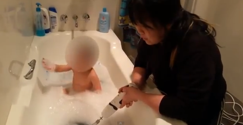 madre baña a su hijo con una batidora en el agua