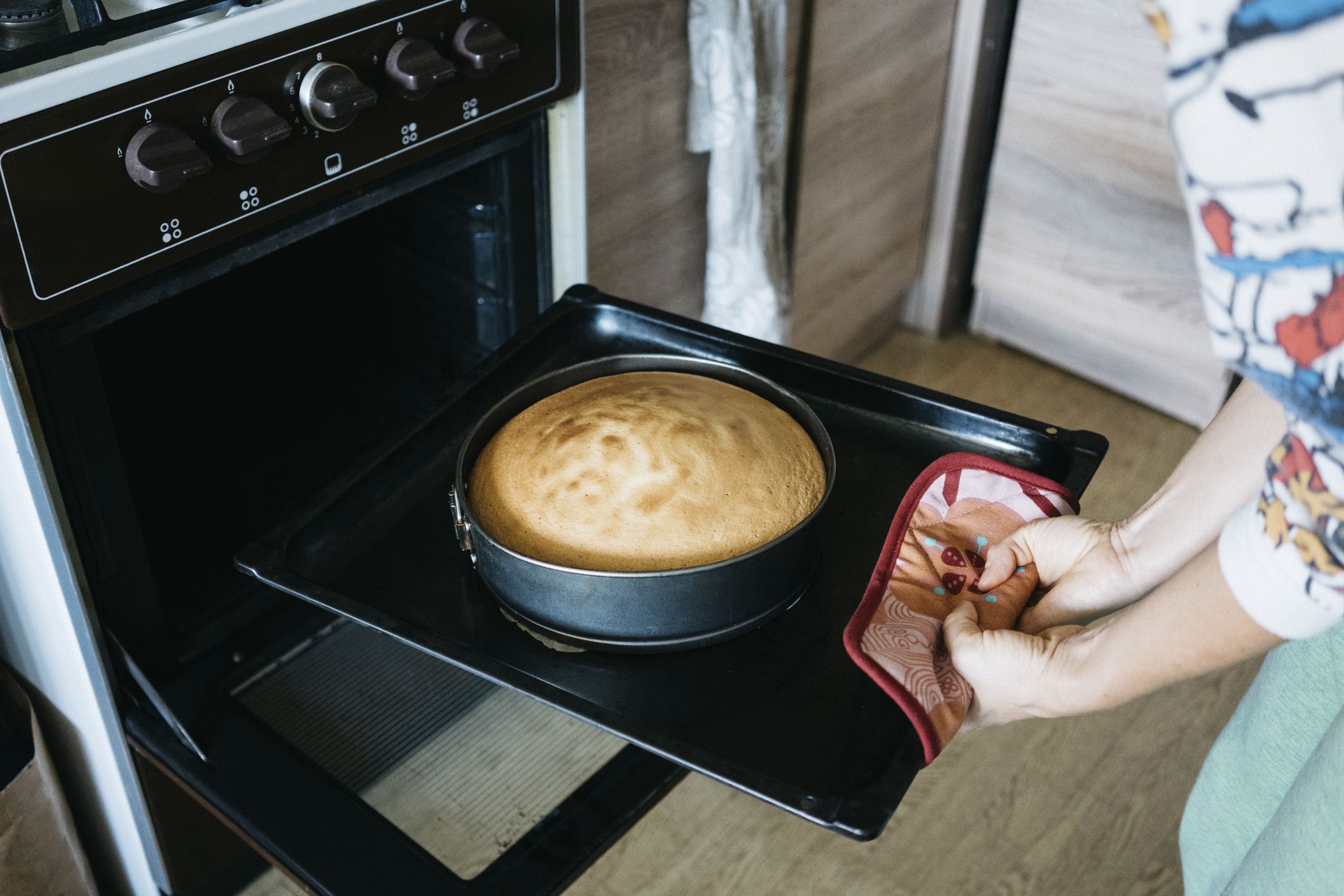Midsection of woman preparing cake in oven at home