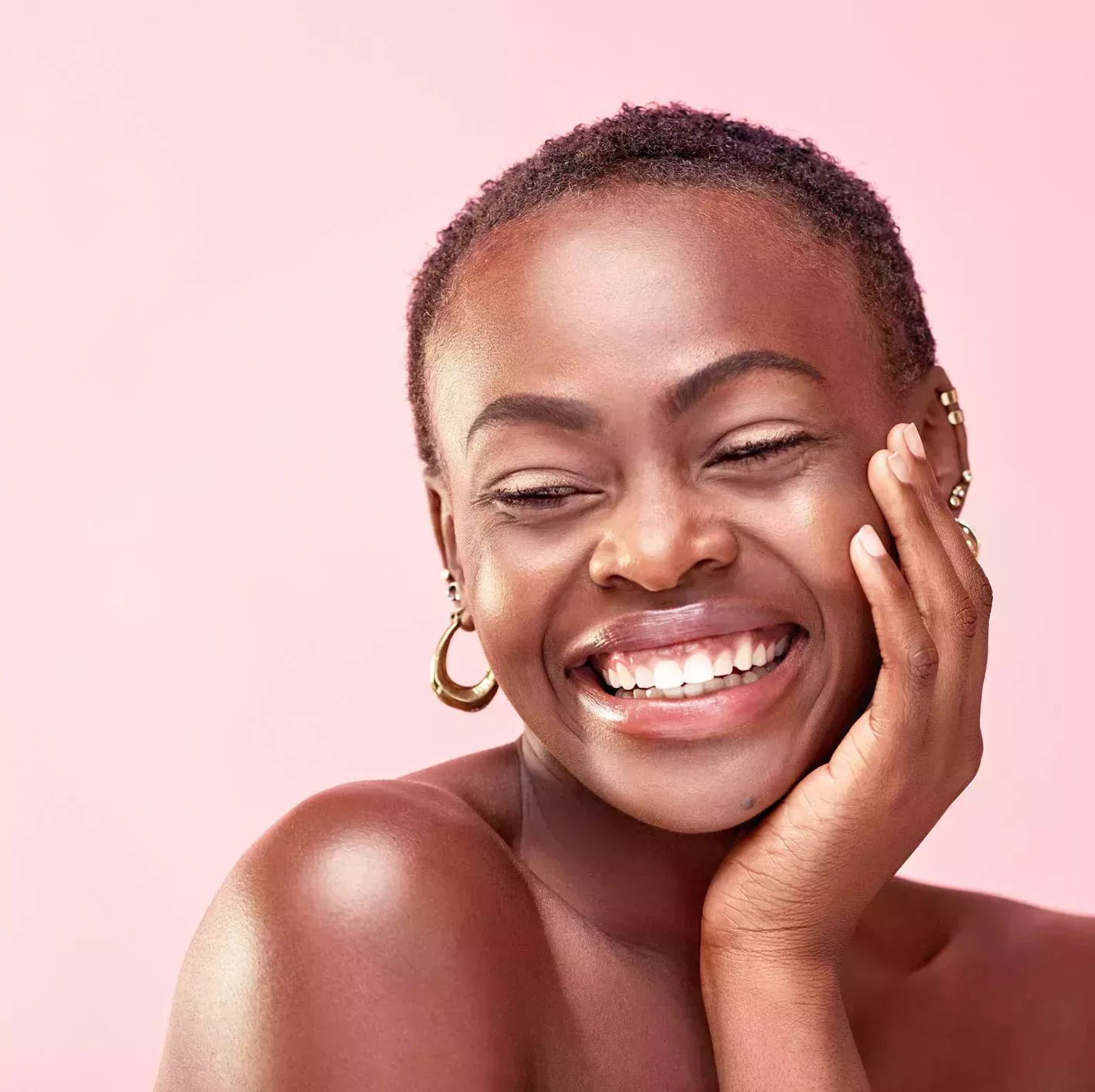 studio shot of a beautiful young woman posing against a pink background