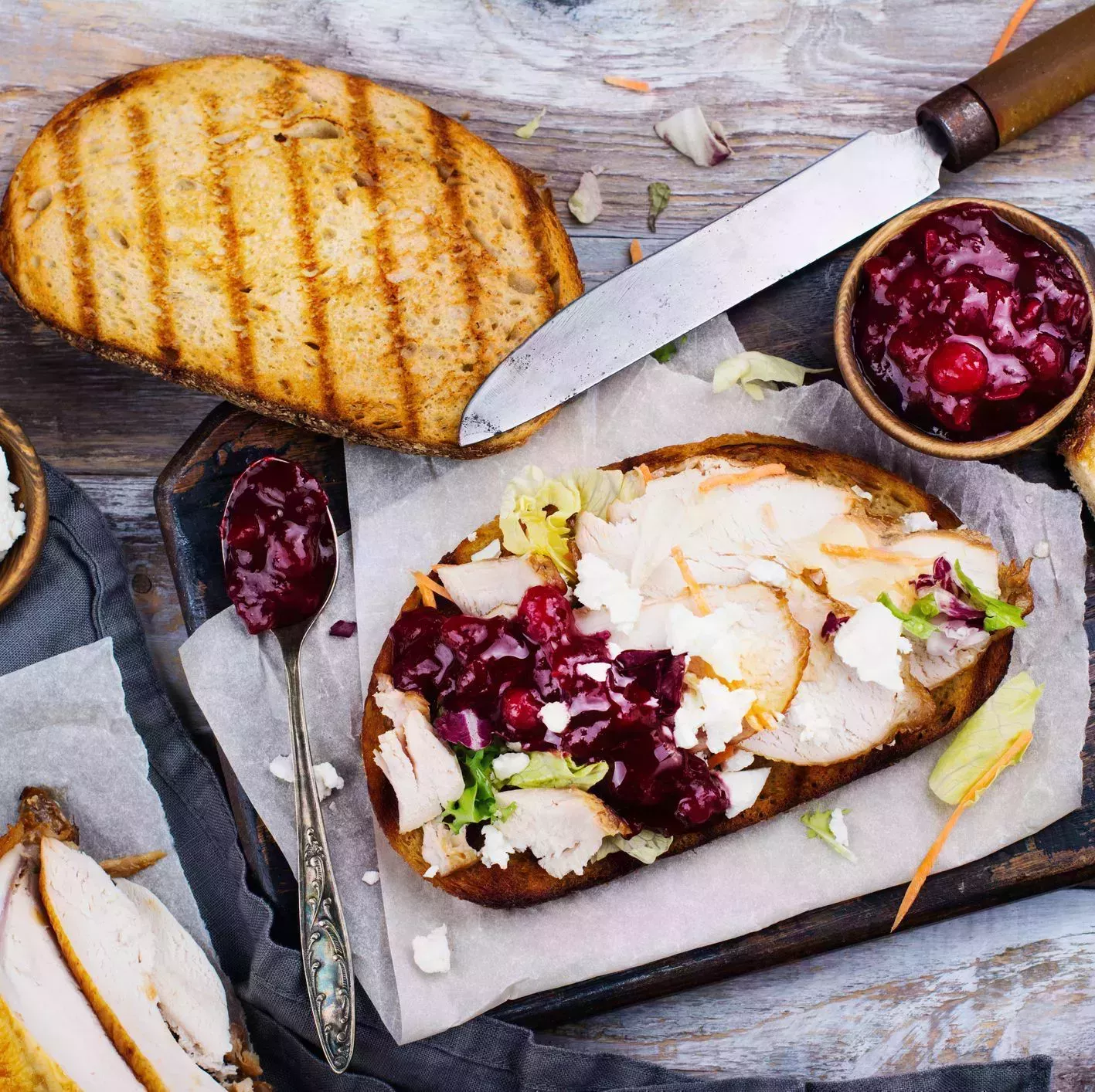 homemade leftover thanksgiving day sandwich with turkey, cranberry sauce, feta cheese and vegetables top view
