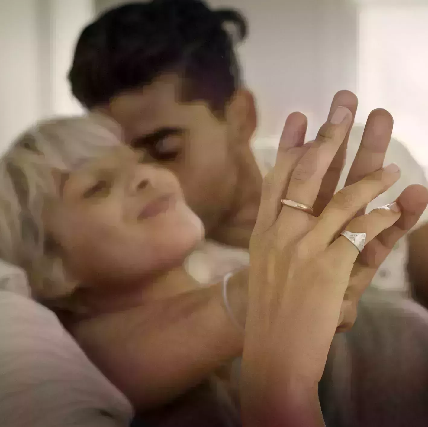 affectionate young man kissing woman while holding hand in bedroom