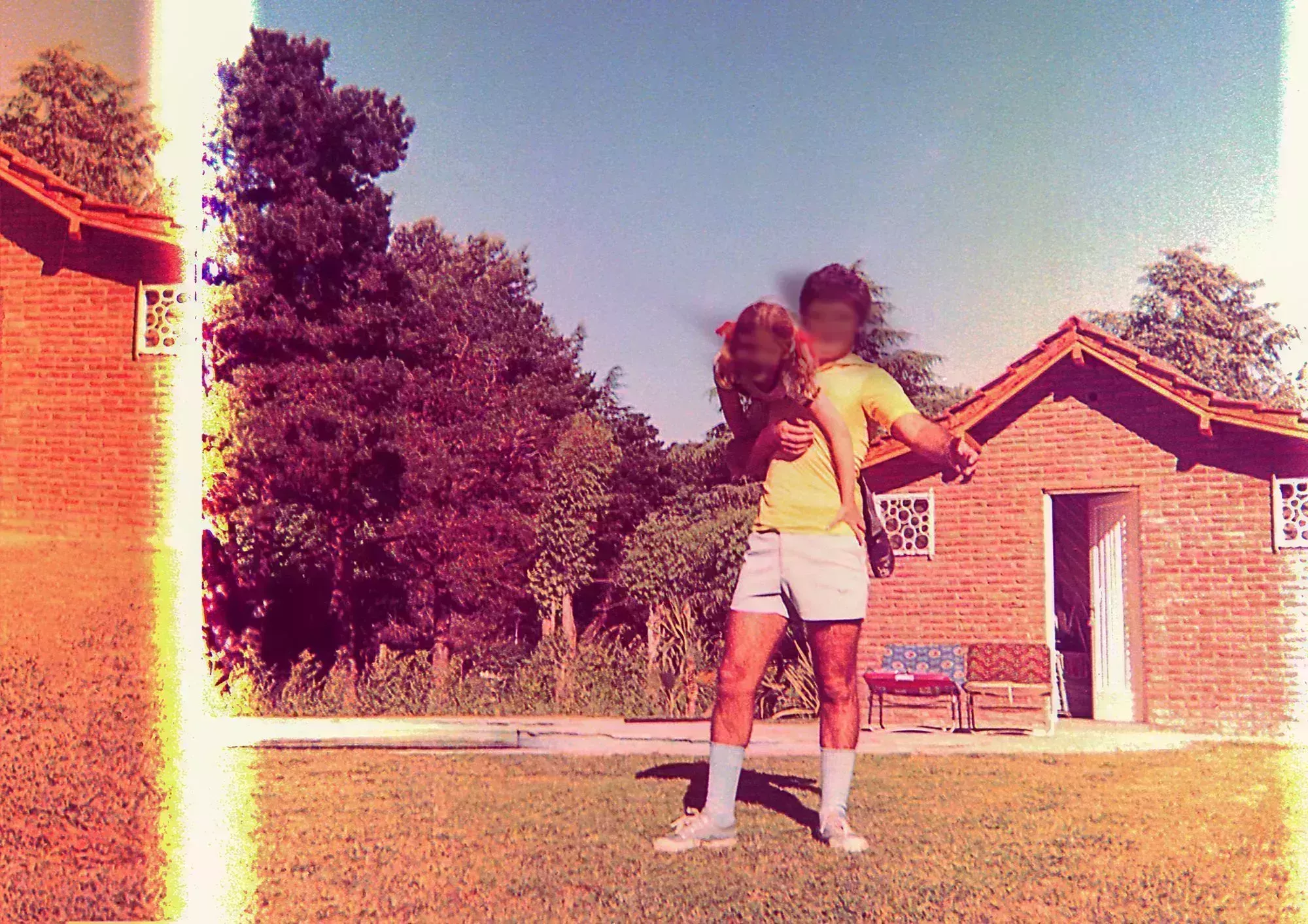 vintage and damaged photo of a girl and her father playing outdoors