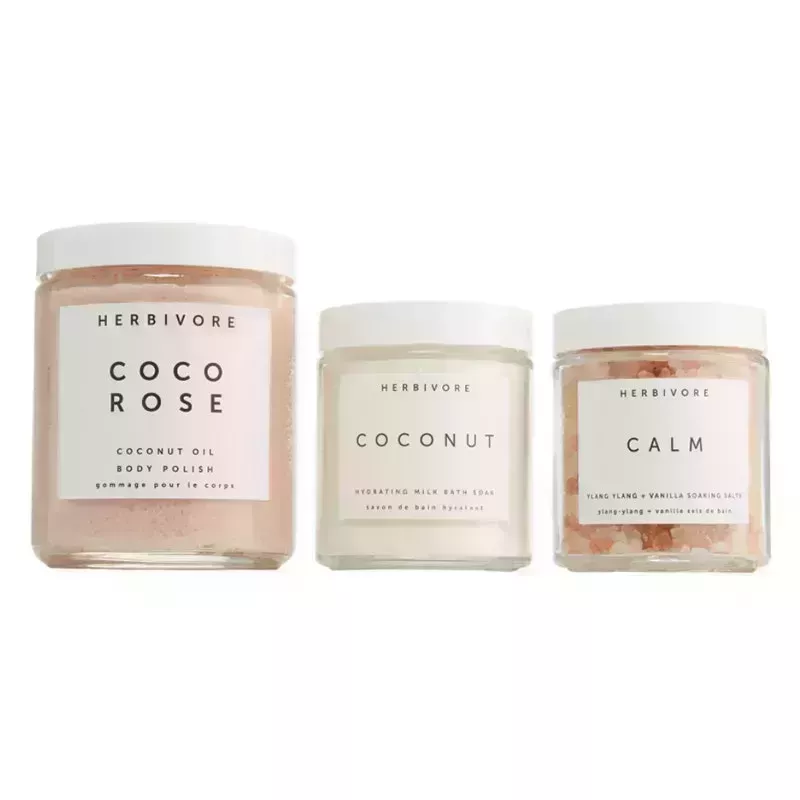 A photo of the Herbivore Botanicals Coco Rose Body Polish Trio, including three jars of the brand's pink and white body care products, on a white background