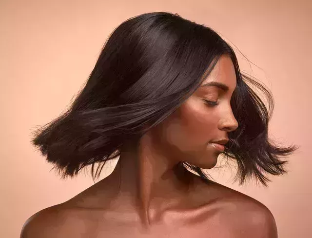 shot of a young attractive woman tossing her hair against a brown background