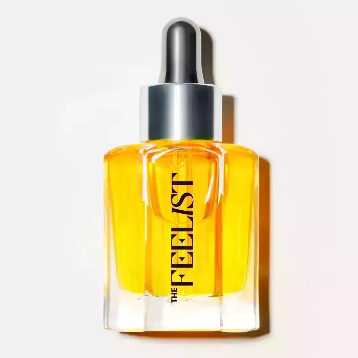 A clear bottle with a silver cap of facial oil on a white background