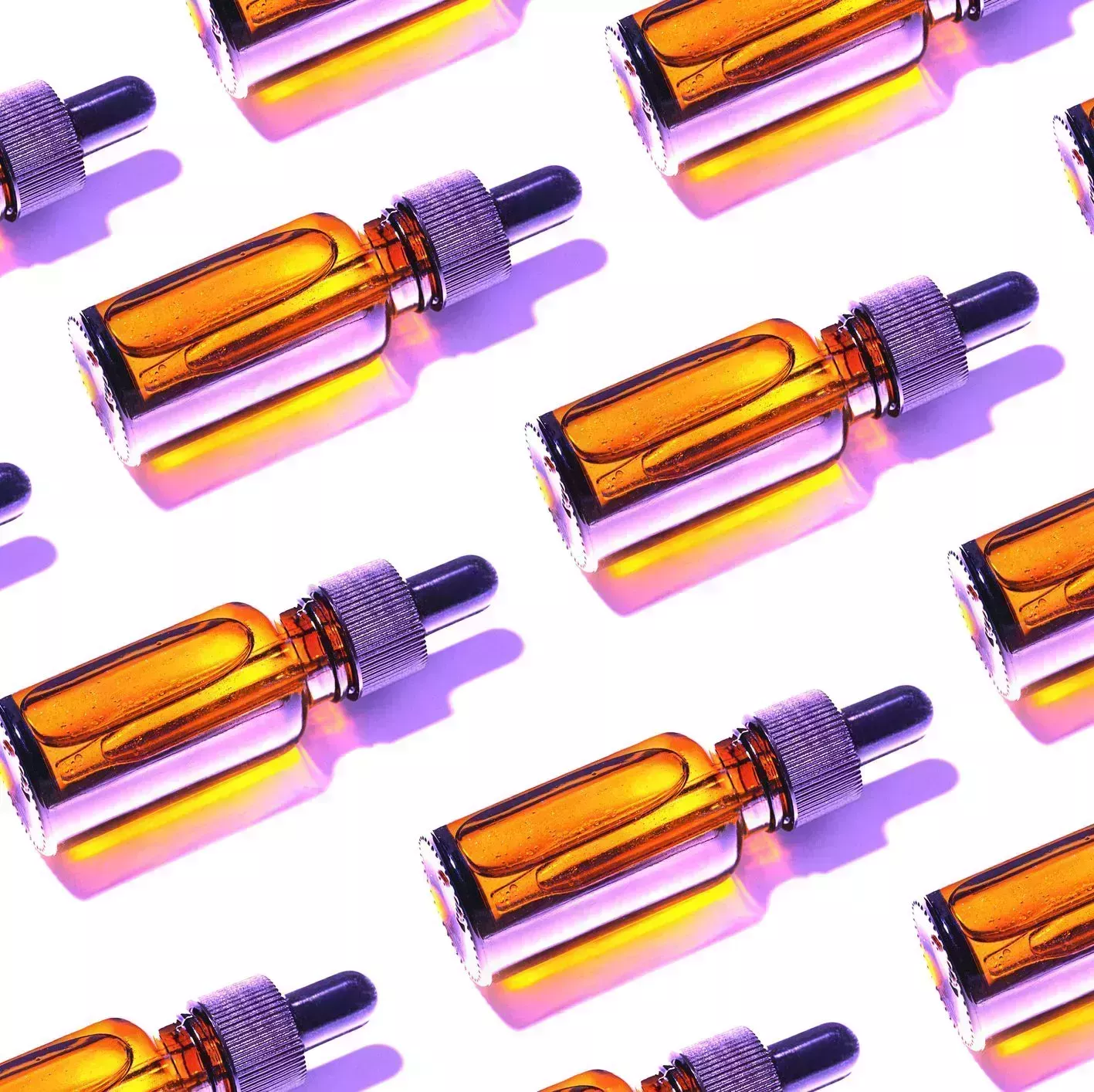 trendy pattern made of beauty product facial serums or natural essential oil in cosmetic bottle with dropper and bright shadow on white background