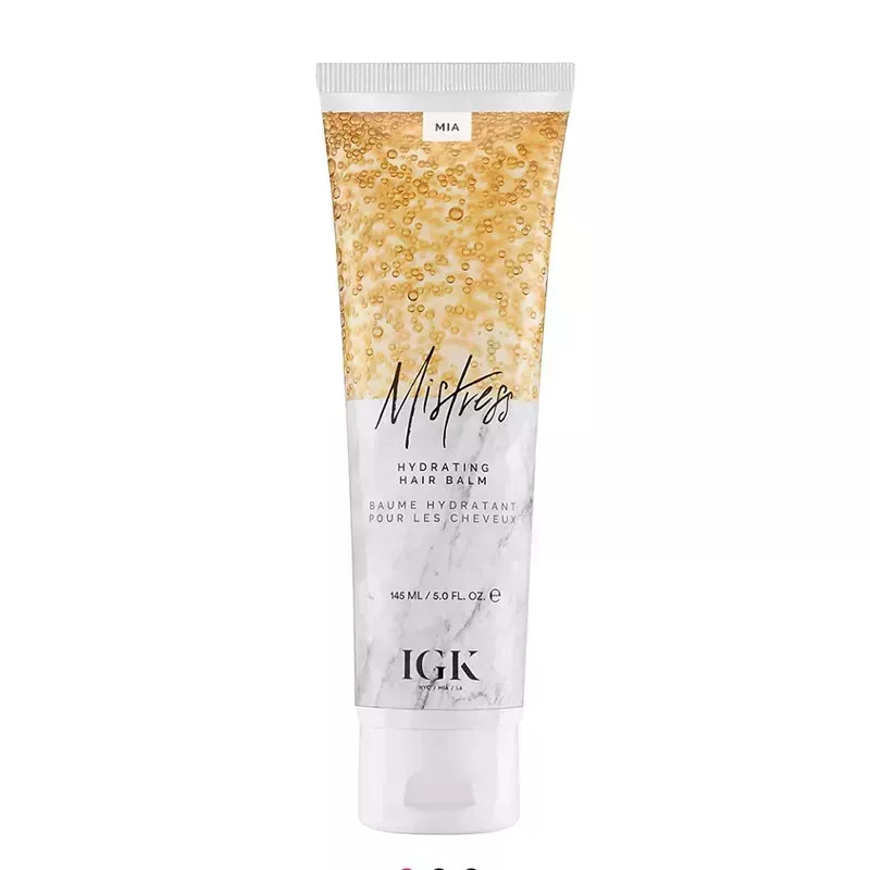 A gold and white bottle of the IGK Haircare Mistress Hydrating Hair Balm