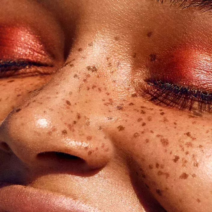 Close up shot of a face with freckles with their eyes and eyebrows taken at a side view 