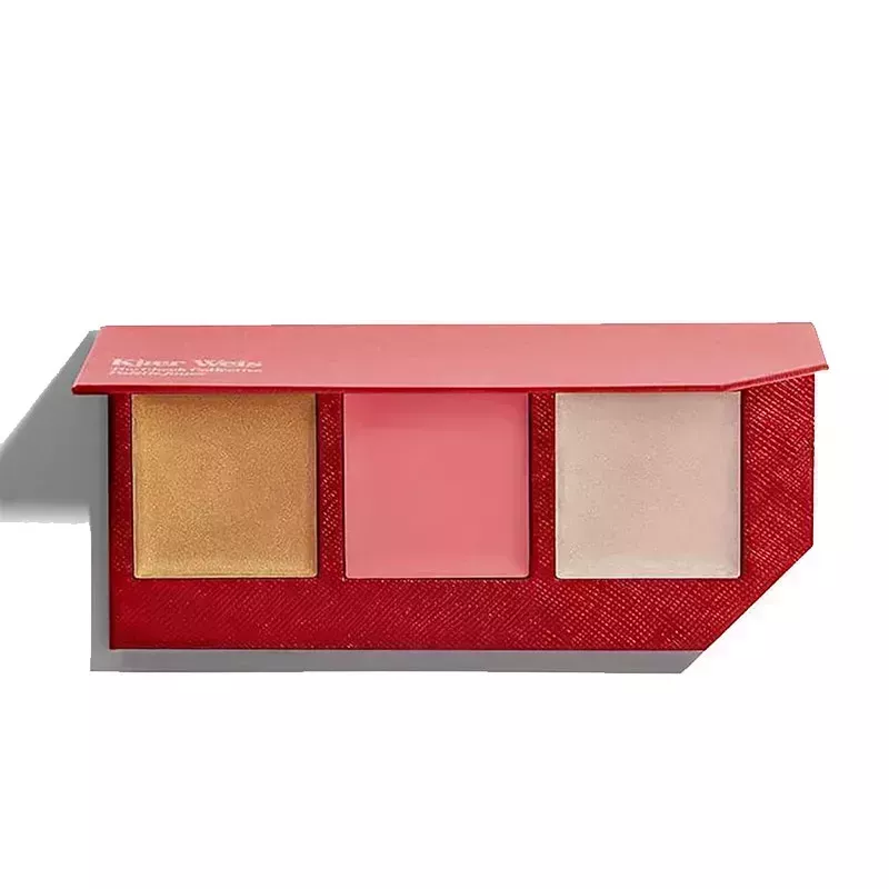 A red makeup compact filled with three pans of highlighter and blush from the Kjaer Weis The Cheek Collective on a white background