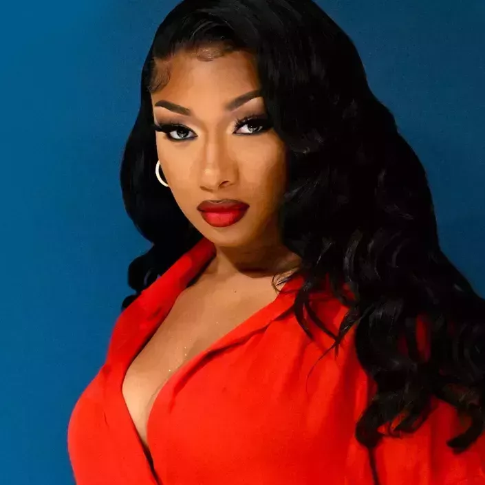 headshot of megan thee stallion with curled black hair, glam makeup, and a deep red lip