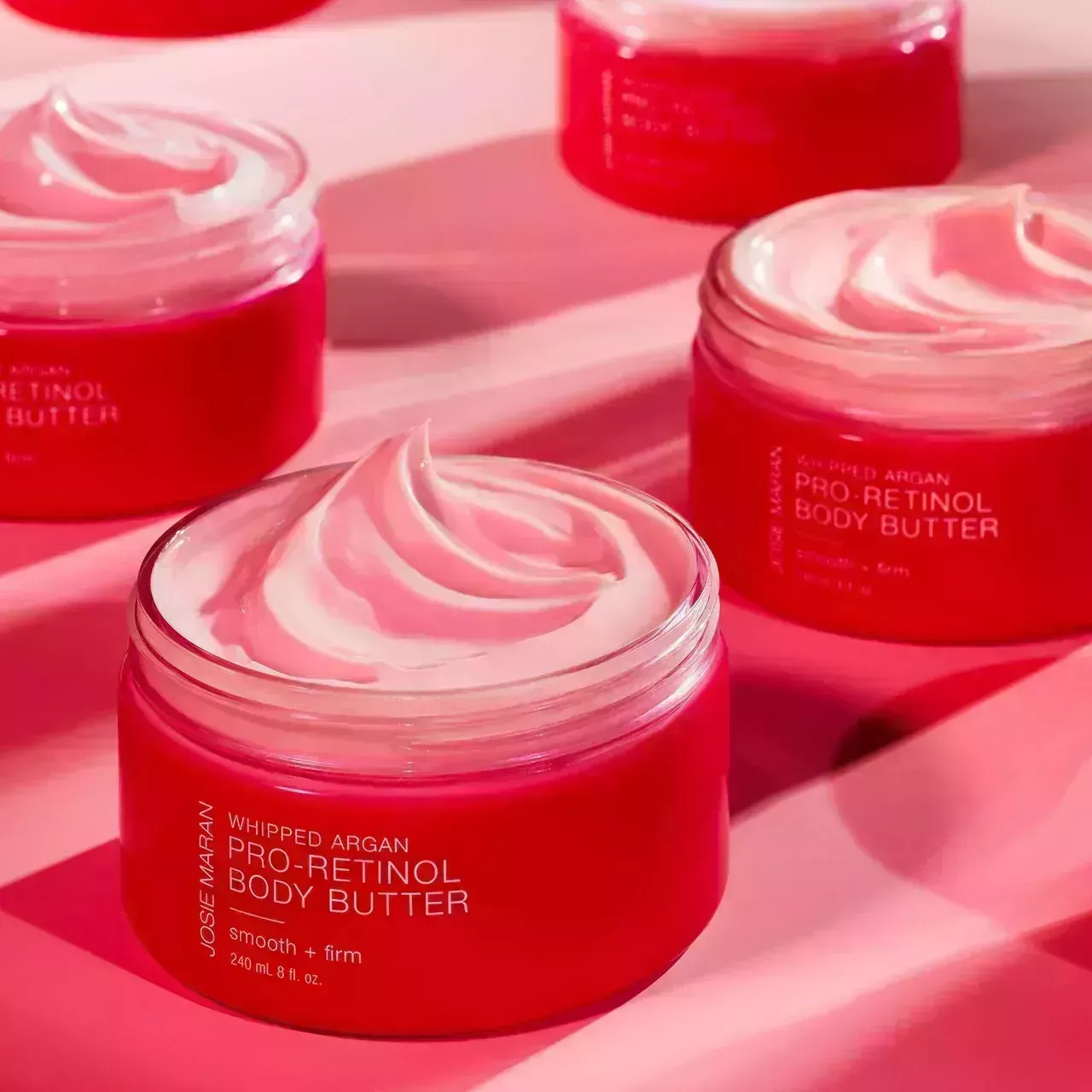 Josie Maran Pro-Retinol Whipped Argan Oil Body Butter in Pink Grapefruit pink jars on pink background