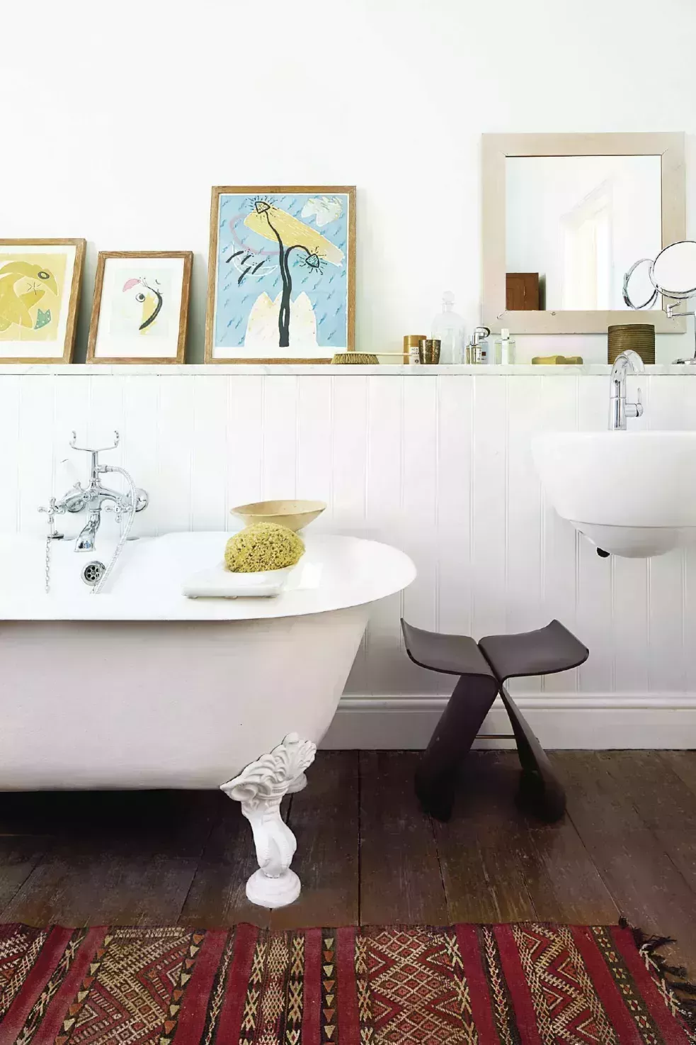 white bathroom ideas, artwork lined on the wall by the bathtub