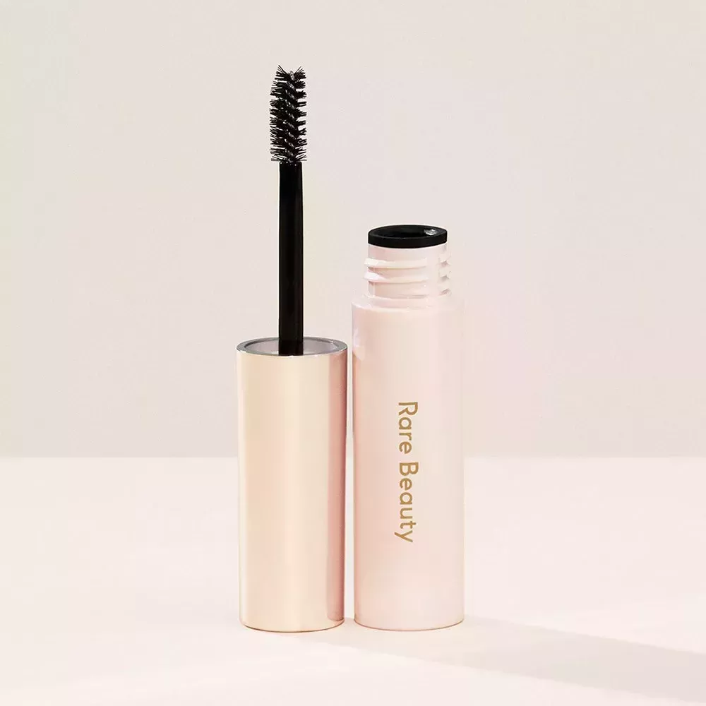 An open tube of Rare Beauty Brow Harmony Flexible Lifting Gel on beige background