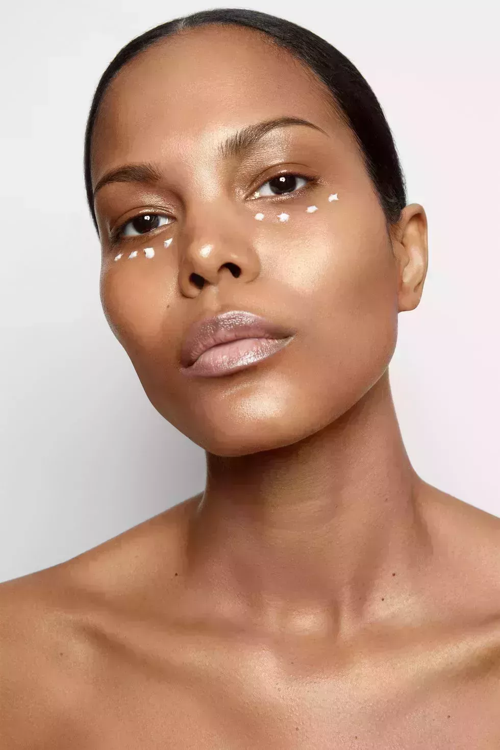 a black woman with dots of lotion under her eyes as she stares at the camera