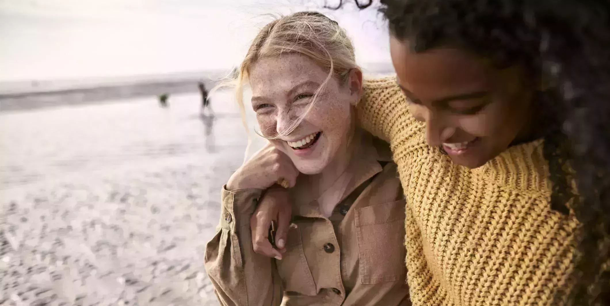 two happy female friends embracing on the beach