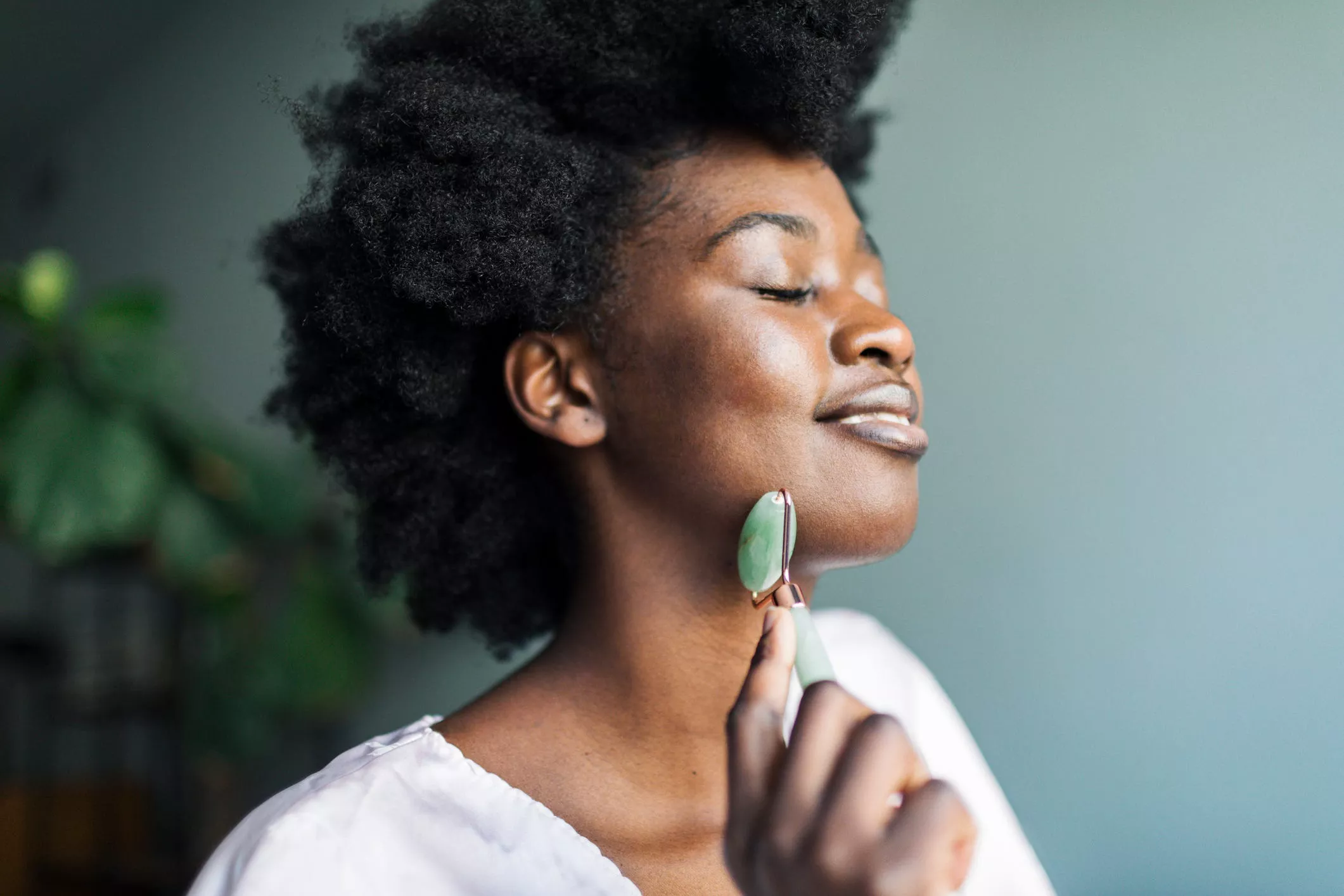 woman using a jade roller to reduce water retention in the face