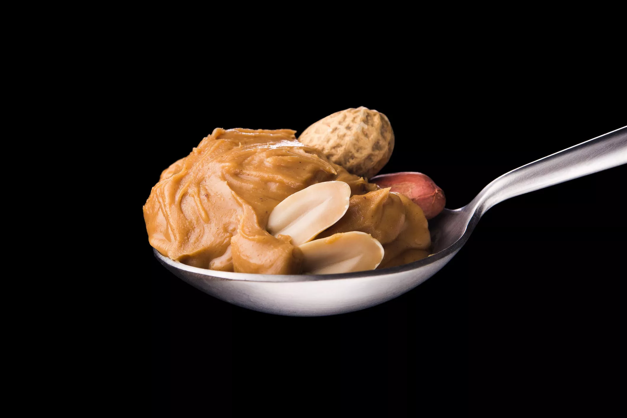 peanut butter on a spoon isolated on a black background