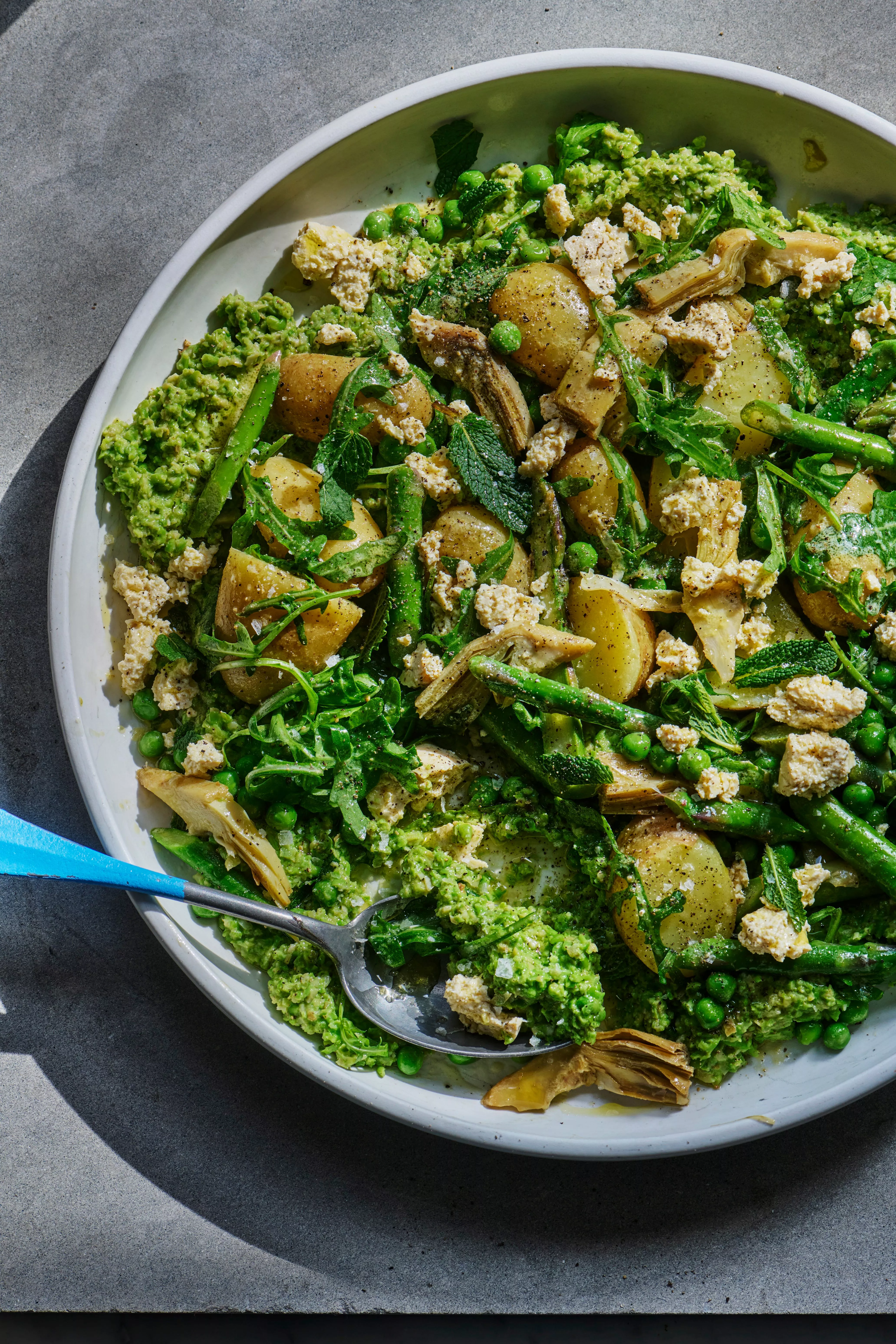 Una imagen de un plato colorido. En el arriado, un guiso elaborado con guisantes, alcachofas y papas.