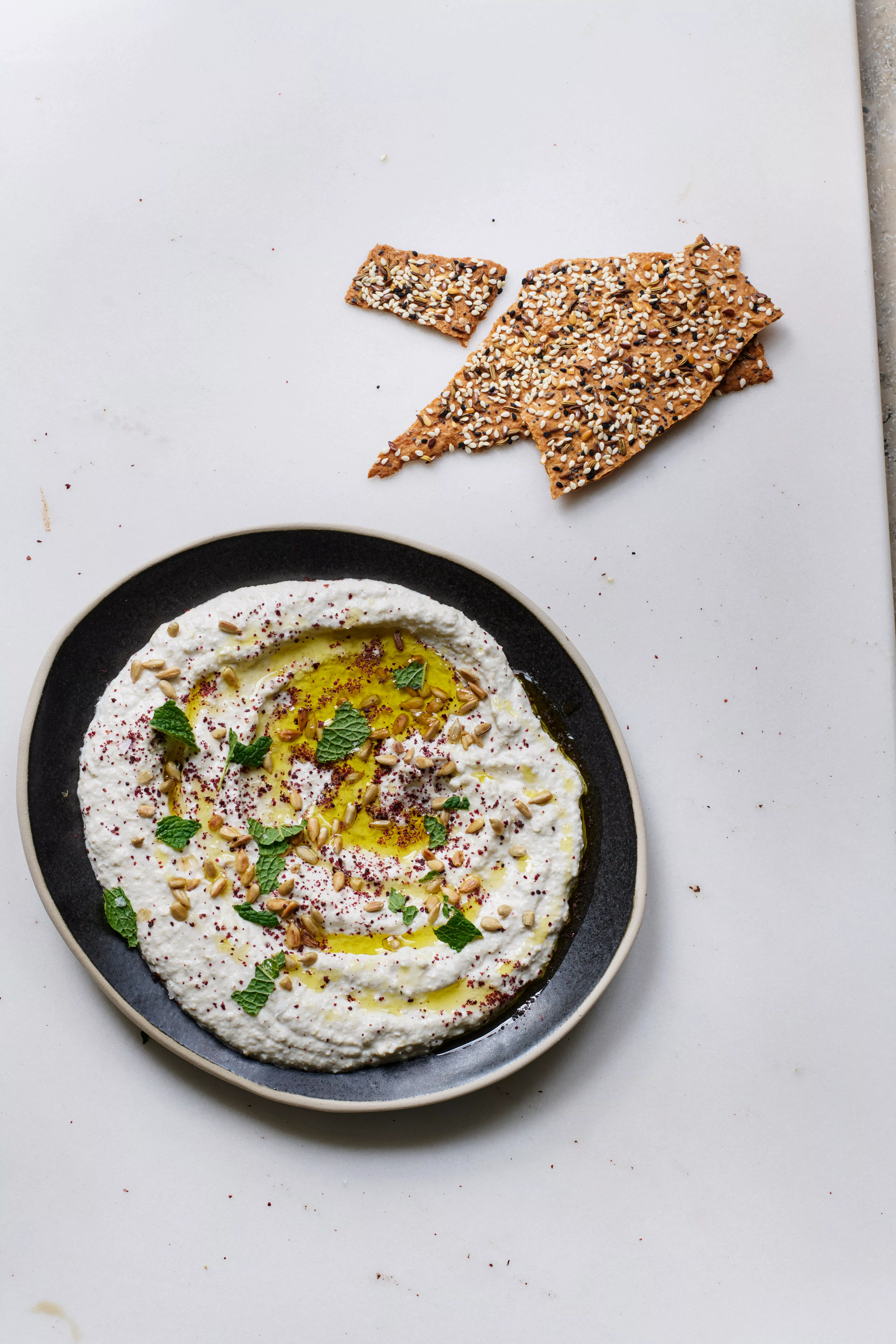 Dip cremoso en un bol, adornado con semillas de girasol y aceite de oliva.