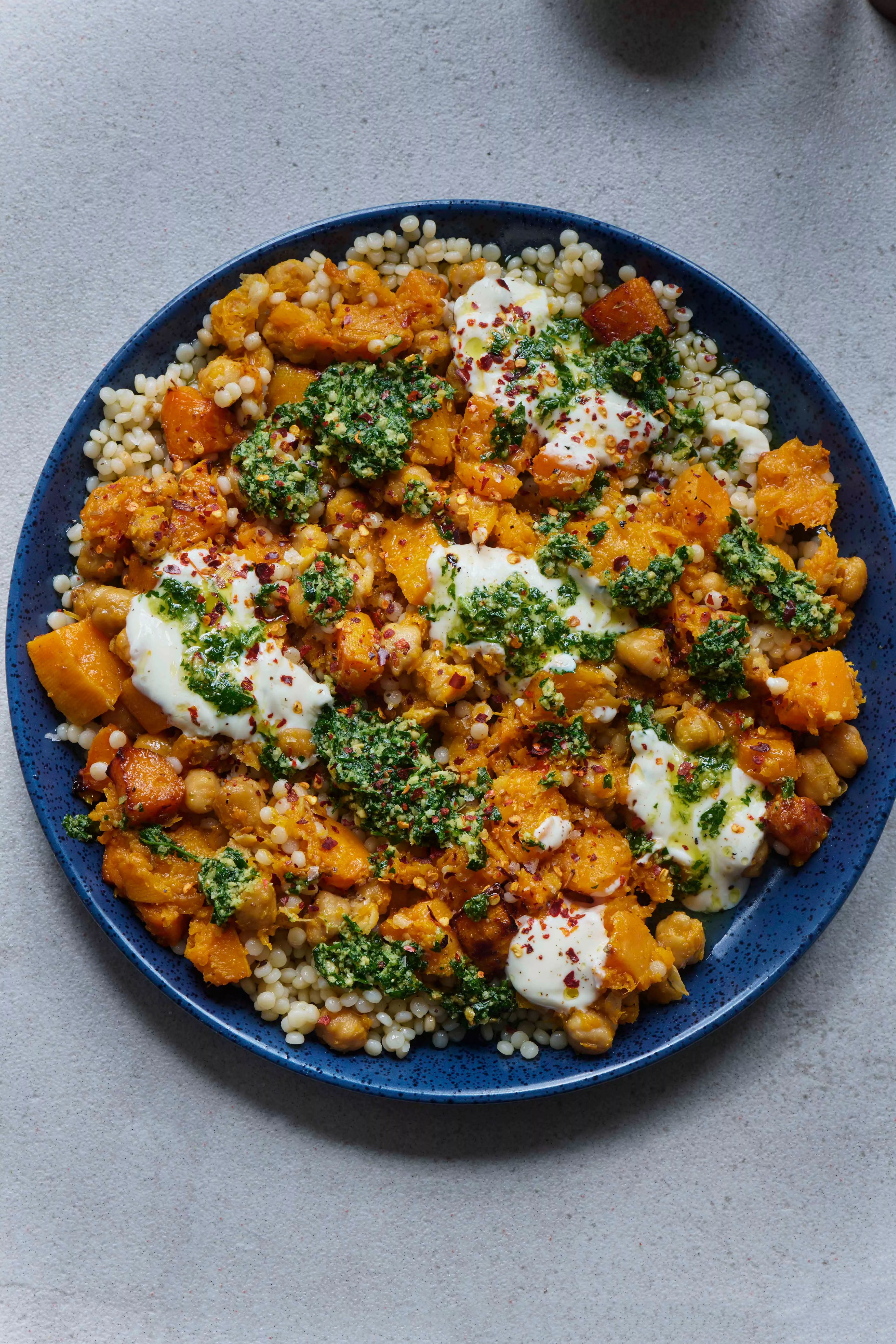 Un plato de calabaza al horno con garbanzos, decorado con gremolata de avellanas.