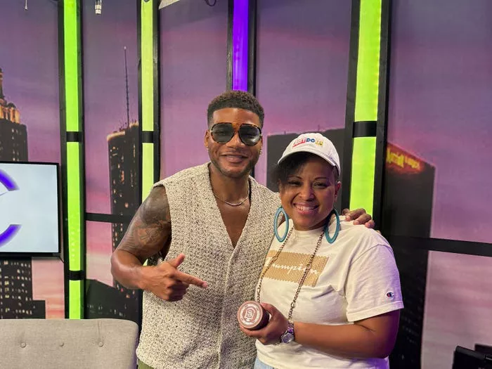 Darrell Spencer junto a una mujer sosteniendo un producto durante la grabación de un programa.