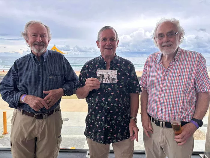 Philip Townsend con dos de sus amigos de toda la vida, sosteniendo una foto de ellos de sus 20 años.