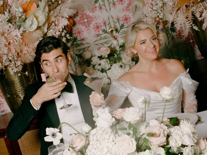 Jacob Hoff y Samantha Wynn Greenstone en su celebración de boda, ambos sosteniendo martinis. Hoff está bebiendo el suyo, mirando hacia un lado, Greenstone sostiene el suyo en alto.