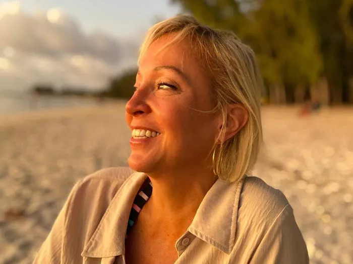 Mujer sentada en la playa con un atardecer.