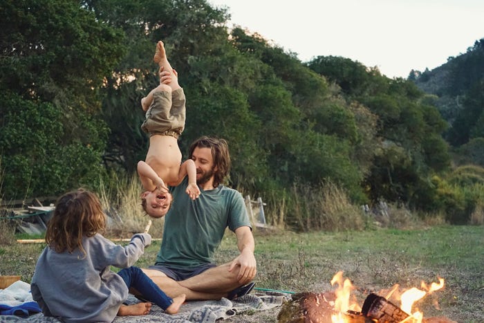 david holding up kid by legs, playing by the campfire